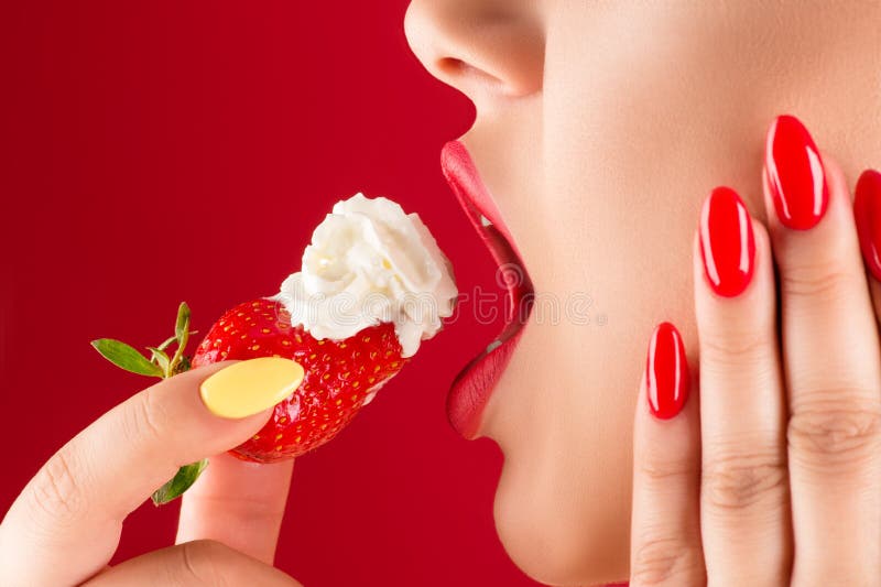 Женщина с чувственными губами ест клубники со сливками. 
