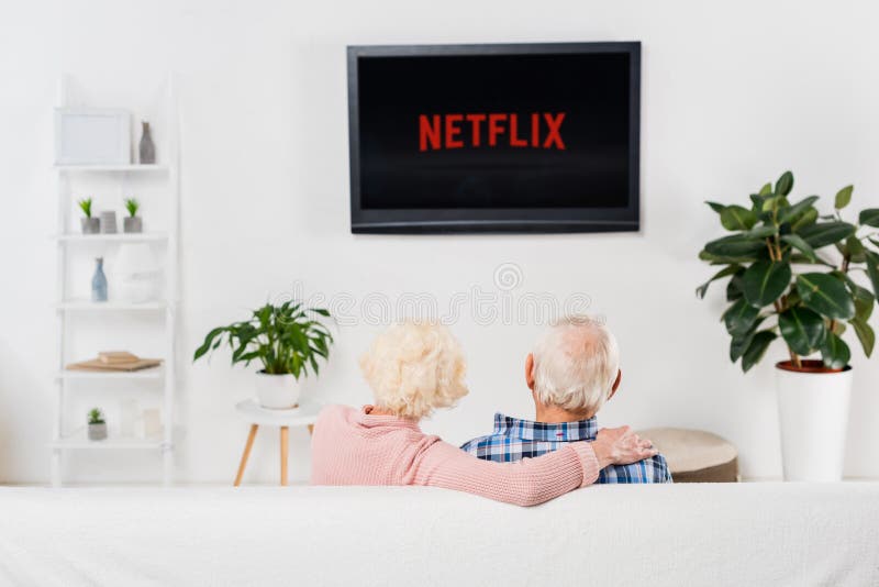 задний взгляд старших пар смотря netflix на ТВ стоковая фотография