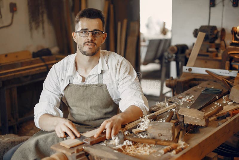 Young african american male carpenter sitting at table showing wooden items thro
