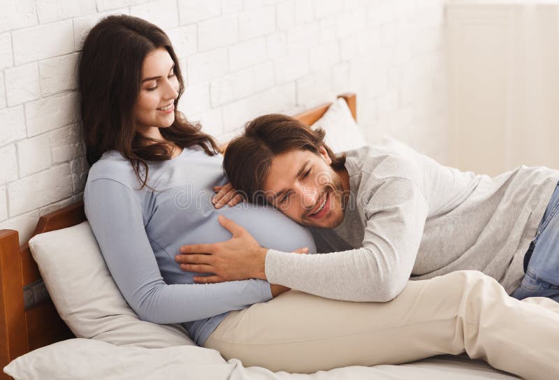 Русские муж и жена в постели. Муж обнимает беременную жену. Кровать мужем и женой купить.