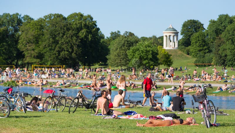 Люди наслаждаясь летним днем в парке города Englischer Garten в Мюнхене, Ге...