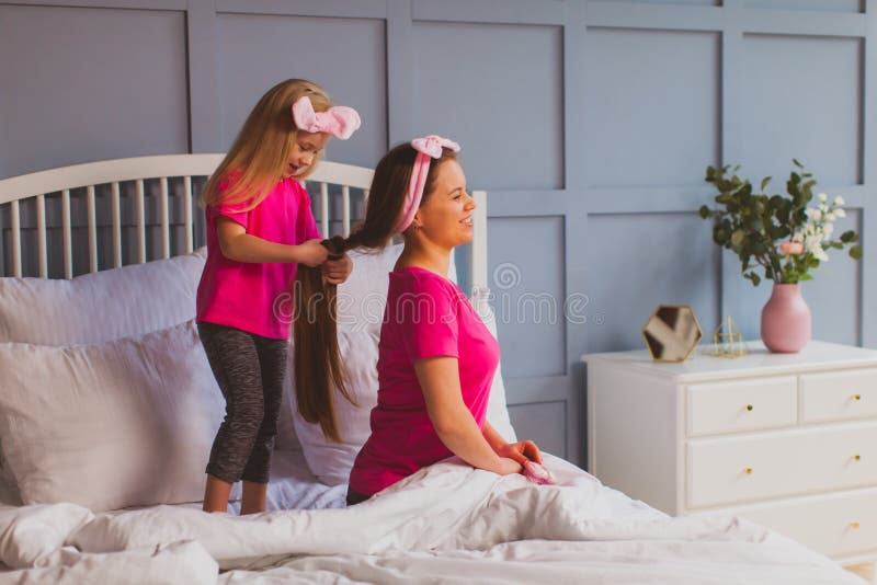 Мама причесывает дочь. Молодая мама расчесывает волосы доченьке. Мама принуждает дочь. Женщина заставляет дочь. Подруга матери заставила