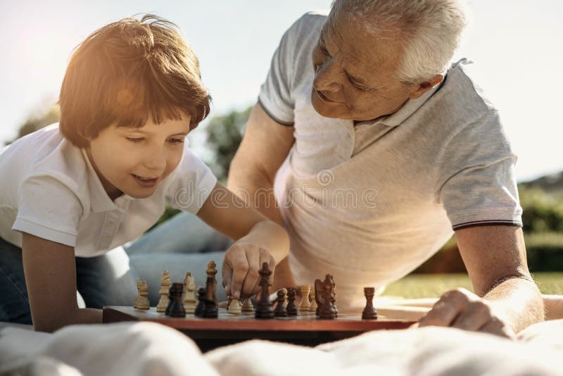 Дед с внуком играют в шашки. Семья играет в шахматы. Дедушка с внучкоиграют в шахматы. Дед и внук играют в шахматы. Дедушка с внуком играют в шахматысунок.