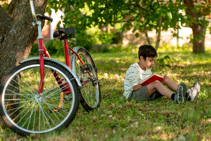 Мальчик сидит на велосипеде. Красный велосипед для мальчика. Темноволосый мальчик на велосипеде. Детский велосипед лежит на траве.