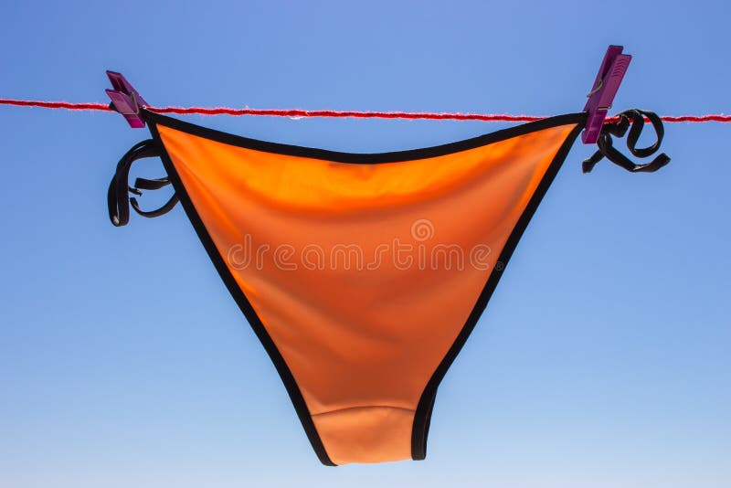 Мокрый купальник на веревке с штырями на пляже. Оранжевый дно бикини на  веревке для сушки белья на фоне голубого неба.. Мода лета Стоковое Фото -  изображение насчитывающей высушено, пикник: 196898938