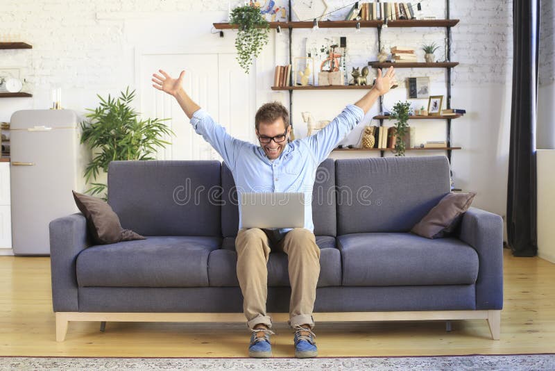 Молодой человек сидит и работает на диване с ноутбуком Стоковое Изображение- изображение насчитывающей успех, комната: 161985665