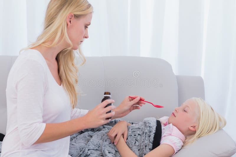 Мама дает внутрь. Стоковое фото мама расстроена. Мама дает дочке таблетку. Daughter Medicine. Mother concerned.