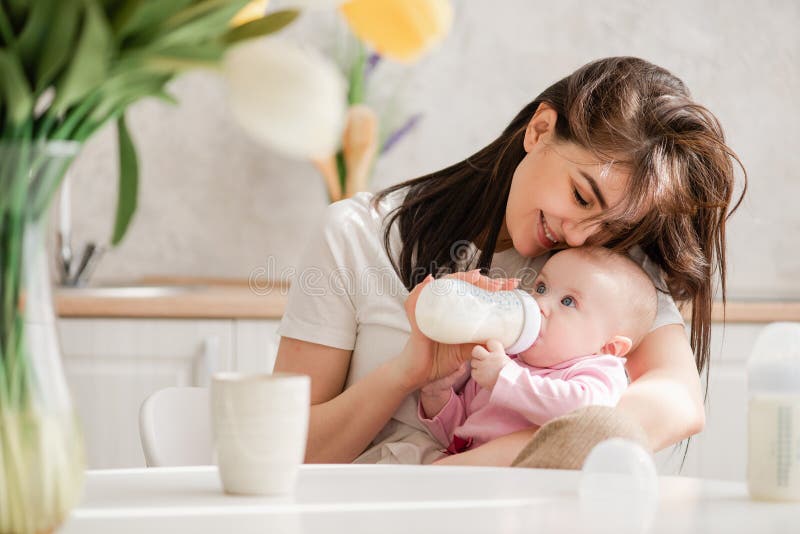 Woman Feeding Newborn with Formula in a Bottle. Stock Image - Image of kitchen, kiss: 145028747