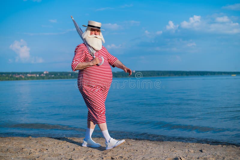 Пожилой мужчина в полосатой ретро купальнике загар на пляже. Старый  Grayhaired бородатого человека в шляпе лежит на Стоковое Фото - изображение  насчитывающей дед, купая: 194681670