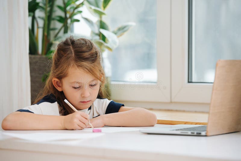 Ребенок учит уроки. Девочка сидит делает уроки. Ребенок пишет. Девочка делает домашнюю работу. Девочка сидит за столом.