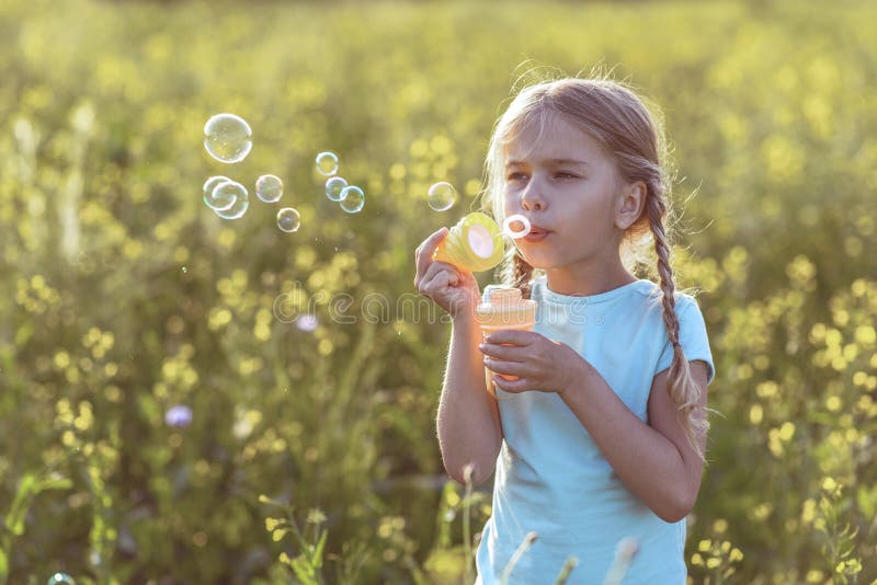 Little Girl Blowing Soap Bubbles Gleaming, Standing