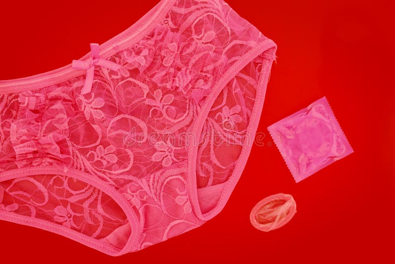 Розовые сексуальные трусы шнурка ` S женщин с презервативом на красной  предпосылке Стоковое Изображение - изображение насчитывающей управление,  влюбленность: 108106649
