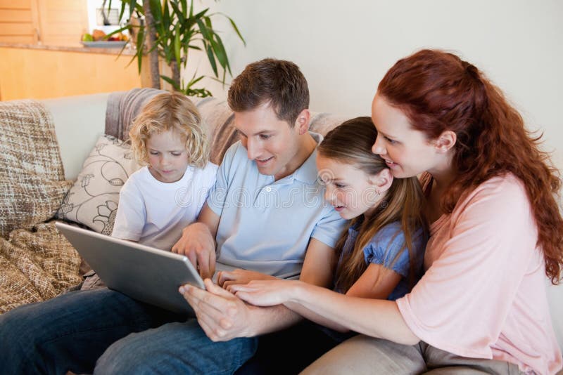 Видео папа мама учит. Семья с ноутбуком. Семья на диване с ноутбуком. Семья на диване с планшетом. Семья на кухне с ноутбуком Фотобанк.