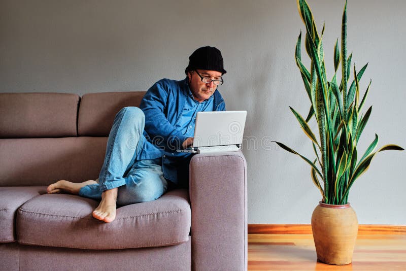 Случайный одетый человек, работая дома сидеть на диване с ноутбукомСтоковое Изображение - изображение насчитывающей привлекательностей, человек:185541543