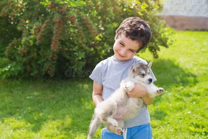 Мальчик держит собаку. Мальчик с щенком в руках. Мальчик держит щенка. Мальчик держит щенка на руках.