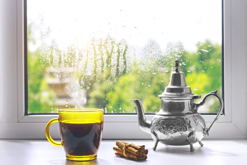 Чашка горячего кофе на windowsill Вне окна дождь