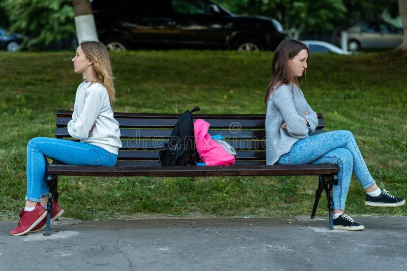 Молодой девушка сидят лице. Две девочки в парке. Две девушки на скамейке. Две девушки на лавке. Подруги сидят на скамейке.