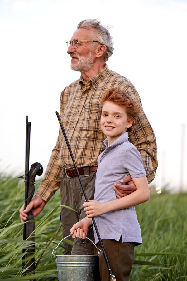 和祖父在湖里钓鱼的小孩. 钓着鱼竿的鱼既开心又兴奋库存照片. 图片包括