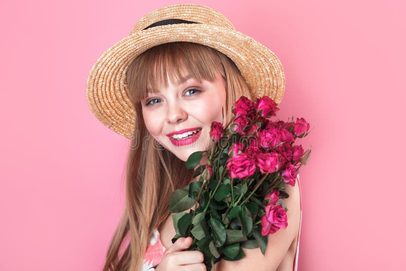 一位穿着夏装 戴着草帽 拿着粉红色背景玫瑰花束的漂亮年轻女子的画像库存照片 图片包括有时兴 礼服