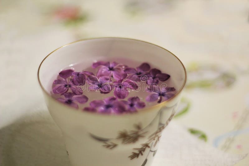 有淡紫色花的被弄脏的杯子在桌布 在减速火箭的言情颜色库存图片 图片包括有