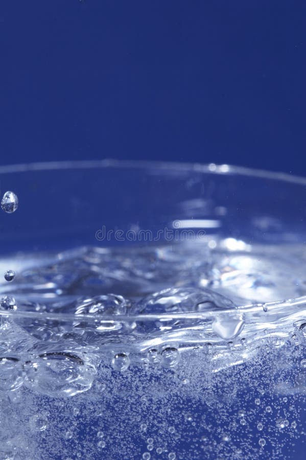 Sparkling water dropping in a glass with many bubbles. Sparkling water dropping in a glass with many bubbles