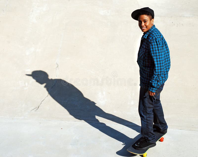 A skater takes a break on a cement ramp, casting an interesting shadow on the ground. A skater takes a break on a cement ramp, casting an interesting shadow on the ground.