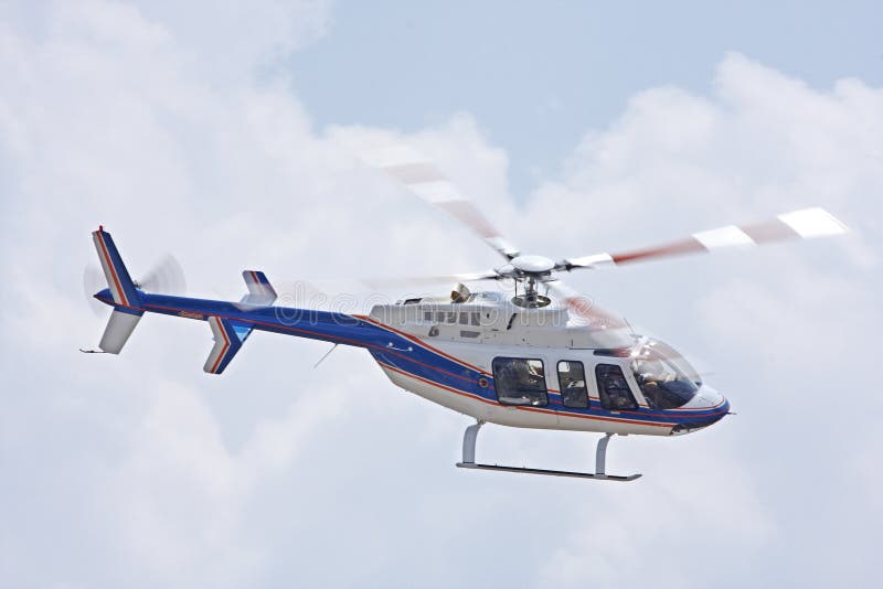 A helicopter flies past against a clouded sky. A helicopter flies past against a clouded sky