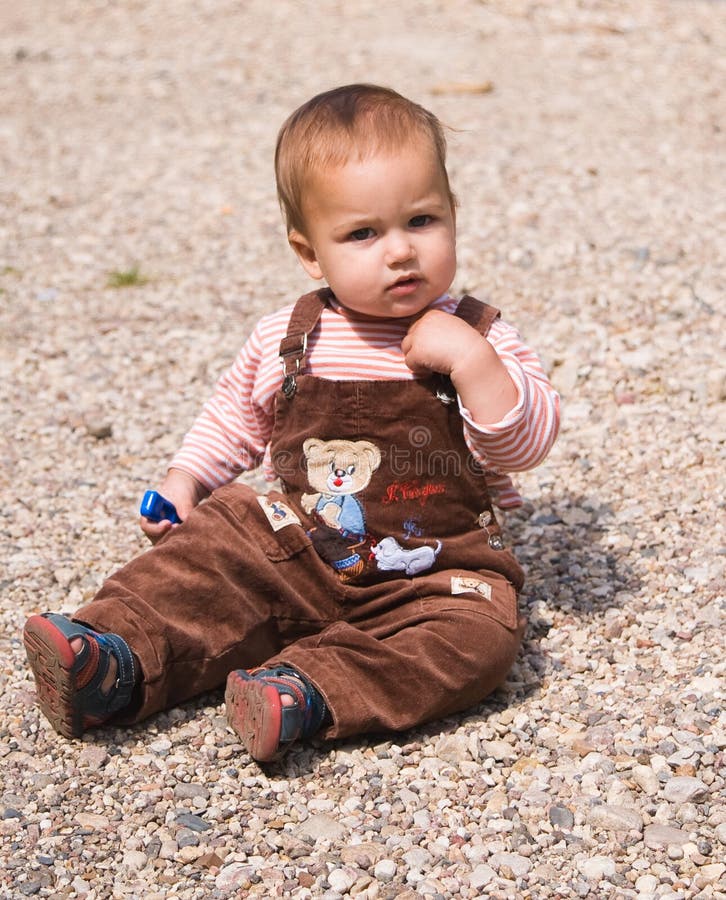 1 year old baby sitting on pebble