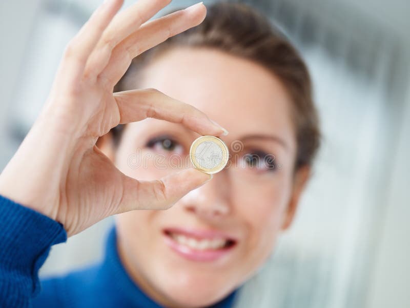 Woman doing ok gesture and showing 1 euro coin. Selective focus. Woman doing ok gesture and showing 1 euro coin. Selective focus