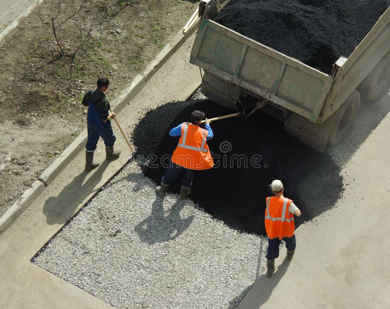 Three workers unload the truck with asphalt. Three workers unload the truck with asphalt