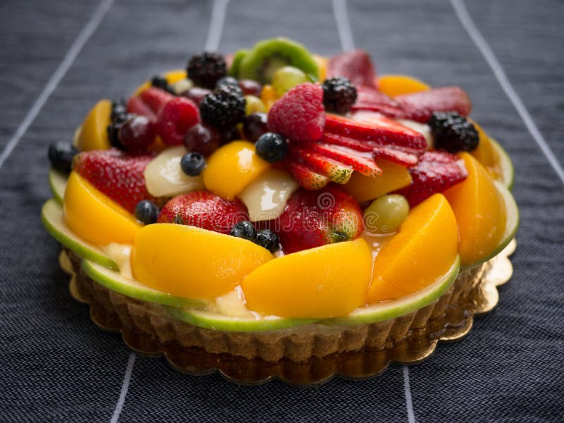 A fresh homemade fruit tart on a tablecloth. A fresh homemade fruit tart on a tablecloth