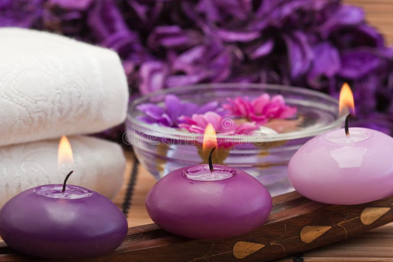 Three purple toned candles and flowers in spa setting (1). Three purple toned candles and flowers in spa setting (1)