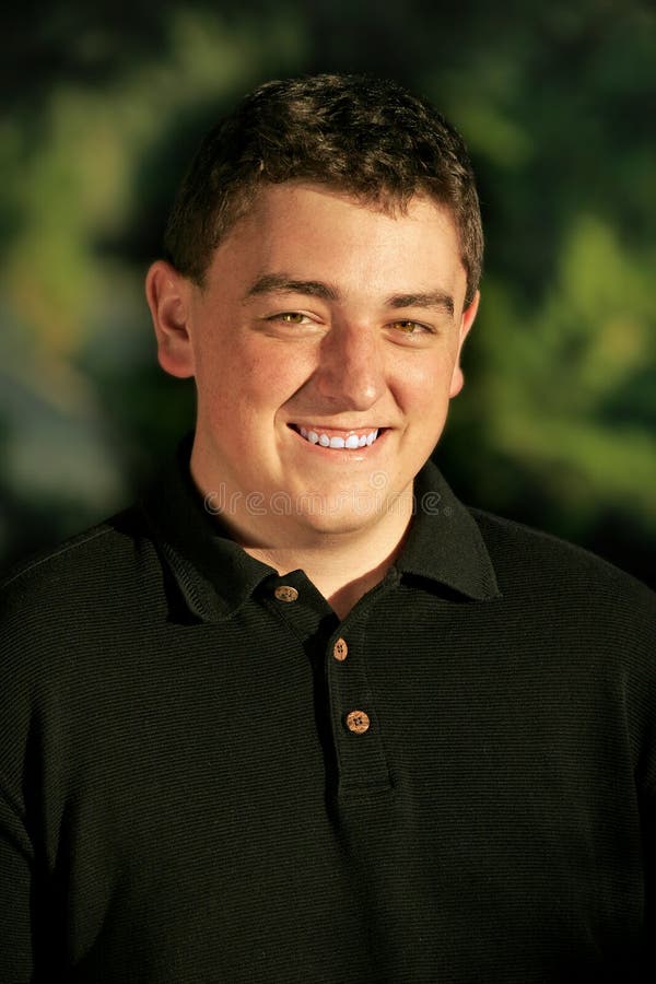 College-aged Caucasian male smiling outdoors in warm-colored, sunset light (shallow focus). College-aged Caucasian male smiling outdoors in warm-colored, sunset light (shallow focus).