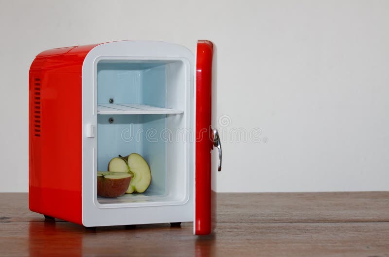 Shiny bright red miniature fridge with apple cut in two parts in it. Shiny bright red miniature fridge with apple cut in two parts in it