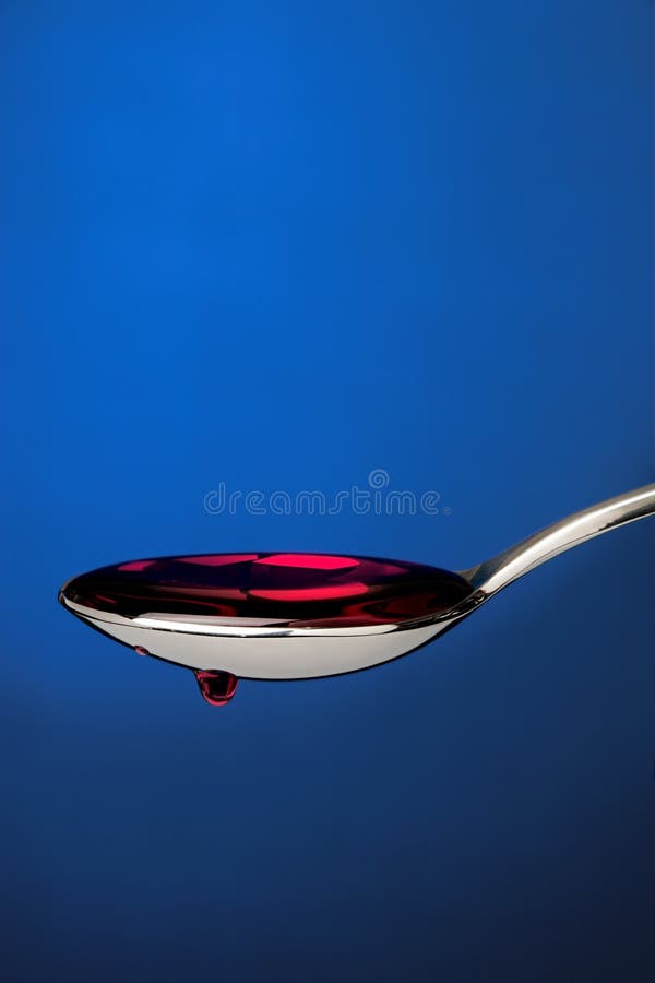 Spoon full of cough medicine over a blue backdrop 2. Spoon full of cough medicine over a blue backdrop 2