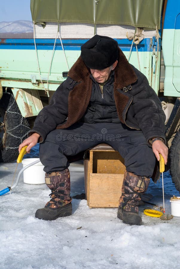 A man on winter fishing on ice of river at car. A man on winter fishing on ice of river at car.