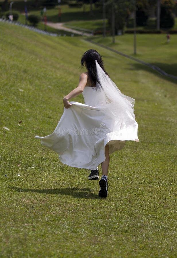 A woman in a wedding dress runs away in training shoes. A woman in a wedding dress runs away in training shoes