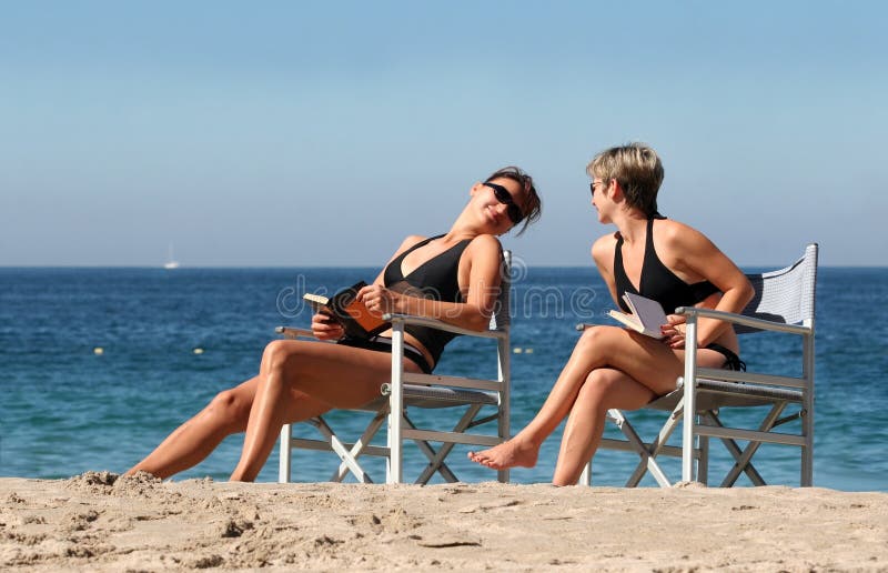 2 women reading on the beach. 2 women reading on the beach