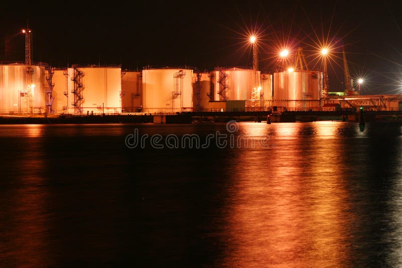 Night oil tanks in the harbor with reflection on the sea. Night oil tanks in the harbor with reflection on the sea