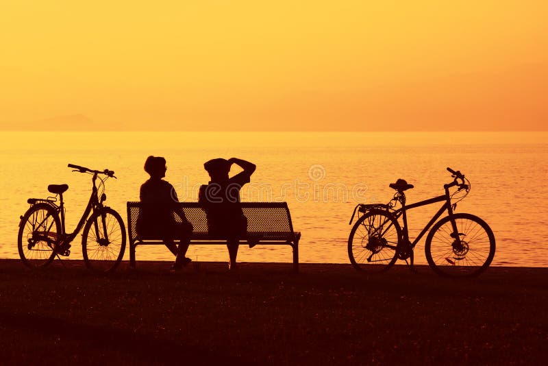 Two cyclists in silhouette overlooking the sea. Two cyclists in silhouette overlooking the sea