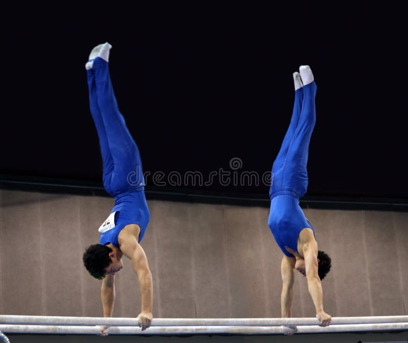 2 gymnasts doing handstand on parallel bars. 2 gymnasts doing handstand on parallel bars