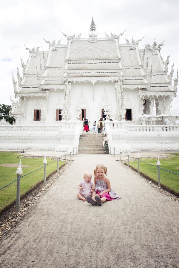 2 little kids sitting in front of White Church in Thailand (Chiang Rai) Wat Rong Khun. travel kids. 2 little kids sitting in front of White Church in Thailand (Chiang Rai) Wat Rong Khun. travel kids