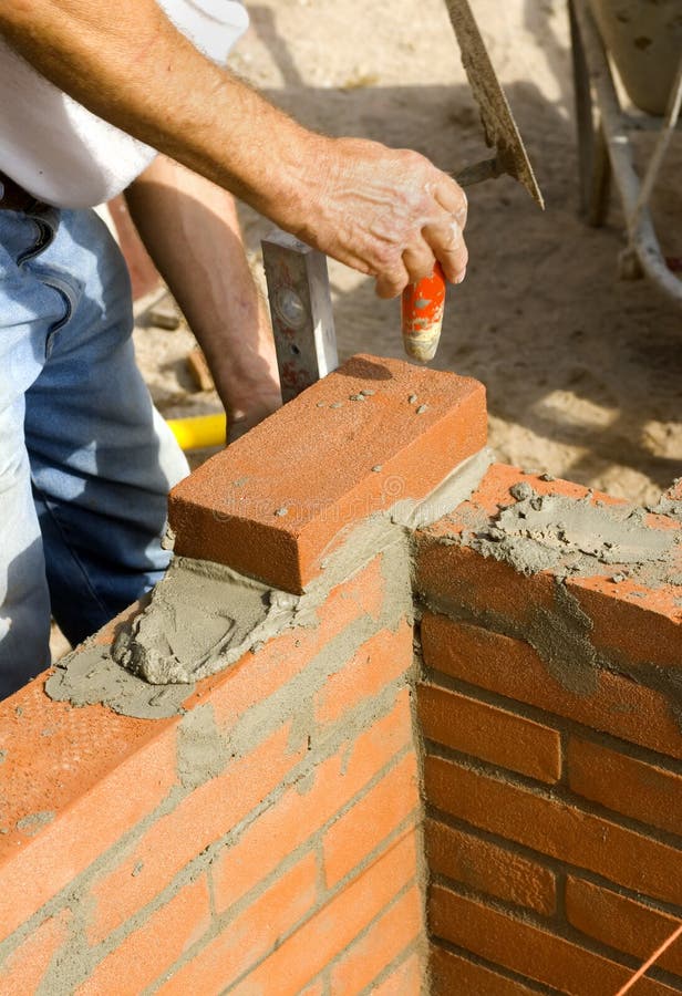 A brick layer levels his bricks as he builds a wall. A brick layer levels his bricks as he builds a wall