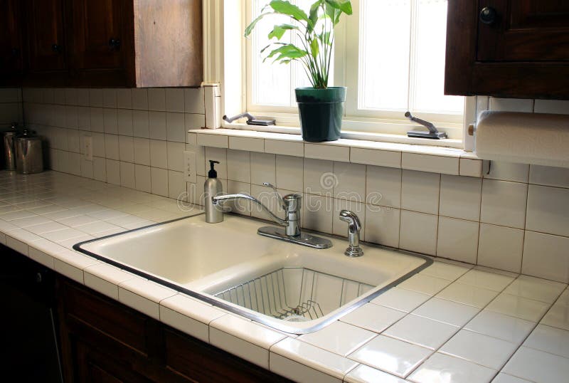 A kitchen sink sits under a bright window and sparkles with cleanness. A kitchen sink sits under a bright window and sparkles with cleanness.