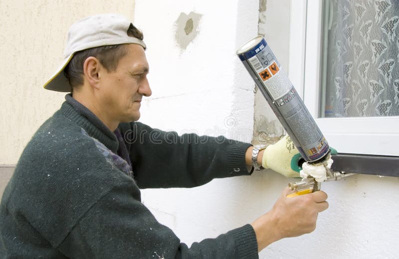 A worker installing a windowsill using a construction foam. A worker installing a windowsill using a construction foam.