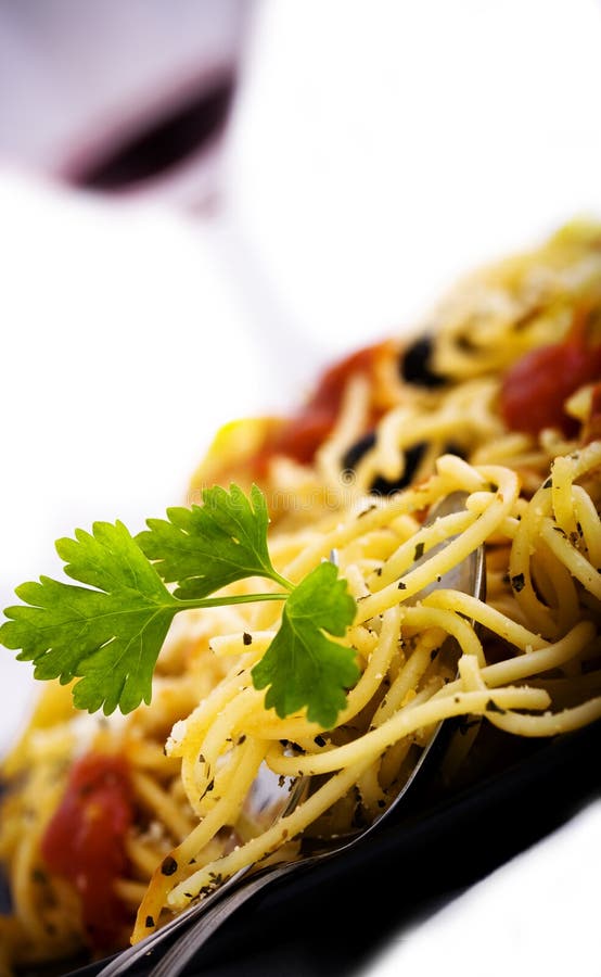 Black plate with pasta and glass of wine in background. Black plate with pasta and glass of wine in background