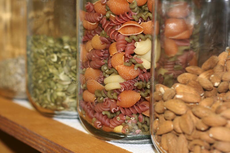 Cupboard containing jars filled with pasta, nuts and seeds. (Primary focus is on the pasta.). Cupboard containing jars filled with pasta, nuts and seeds. (Primary focus is on the pasta.)