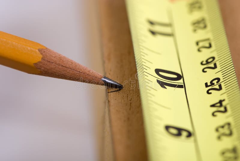 A woodworker measures the mark for his cut. A woodworker measures the mark for his cut