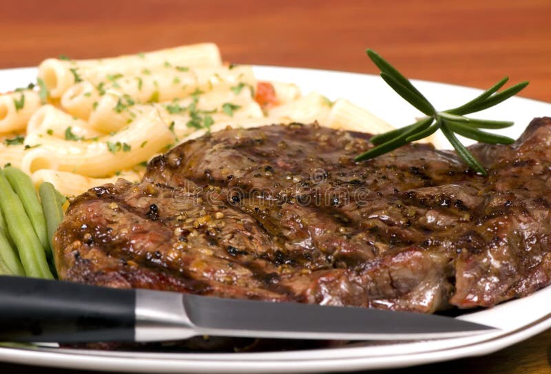 A rib Eye steak with pasta and vegatables. A rib Eye steak with pasta and vegatables