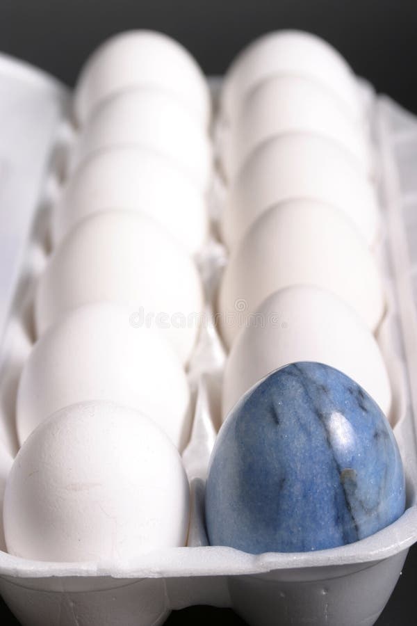 Close-up view of an unusual carton of eggs with a blue marble egg included. Close-up view of an unusual carton of eggs with a blue marble egg included.